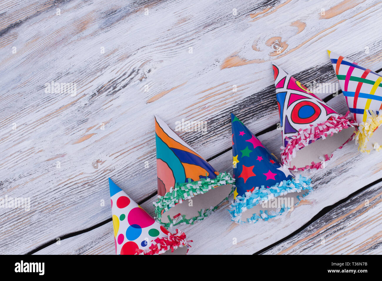 Birthday party items on wooden background. Five Birthday hats with text space, top view. Concept of Birthday party. Stock Photo