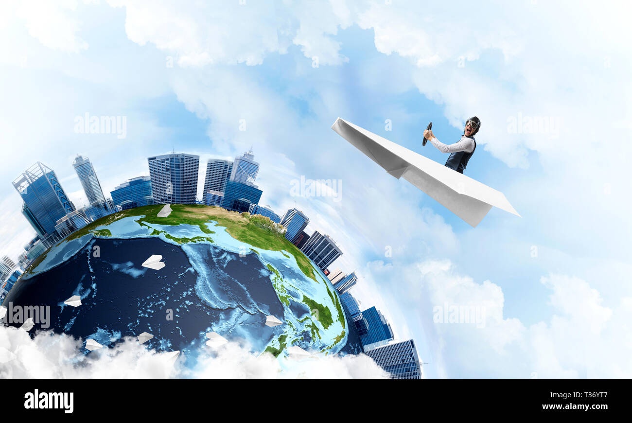 Pilot in leather helmet and goggles driving paper plane in cloudy blue ...