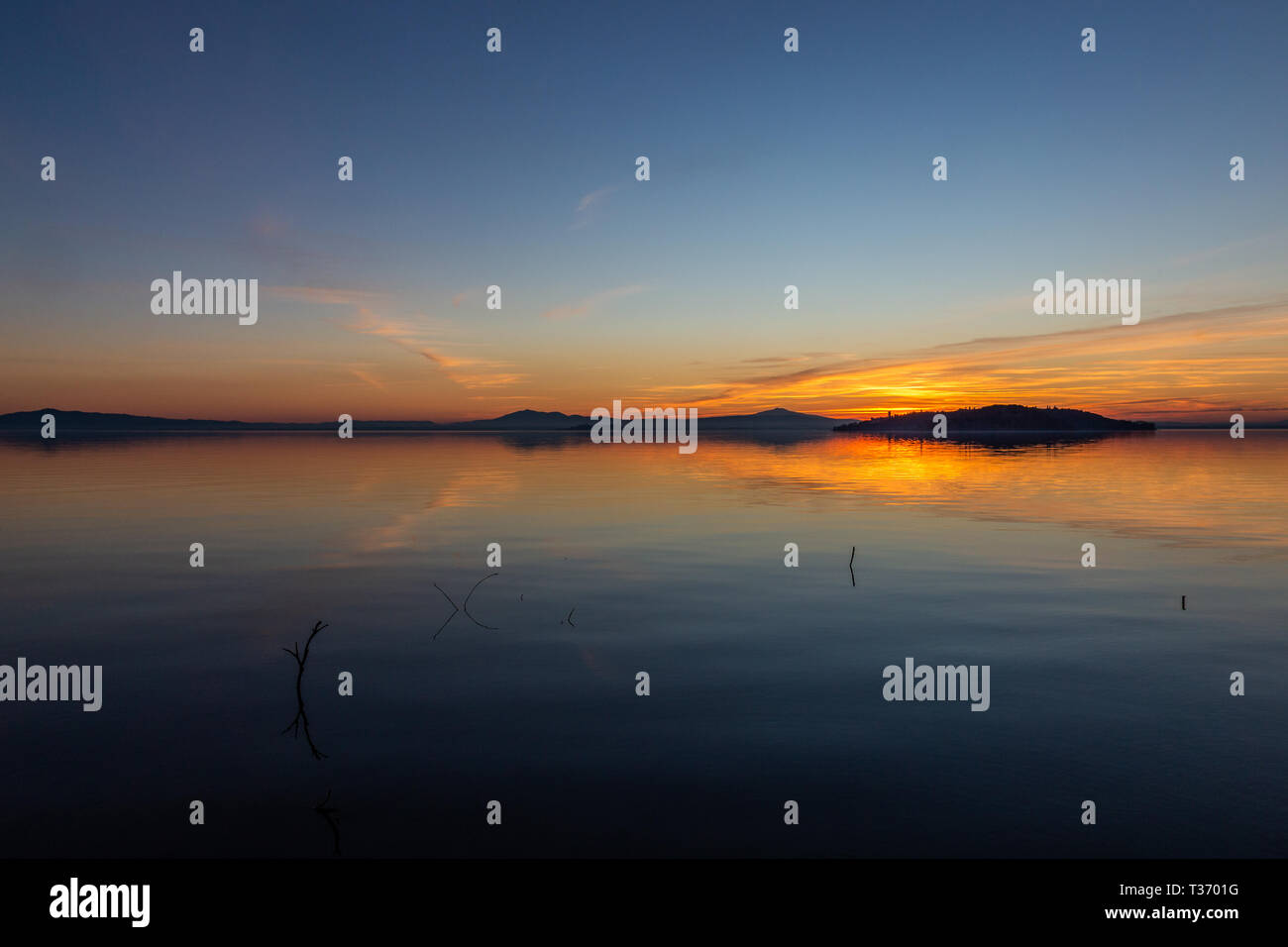 Symmetrcal, beautiful view of Trasimeno lake (Umbria, Italy) at sunset, with orange and blue tones in the sky Stock Photo