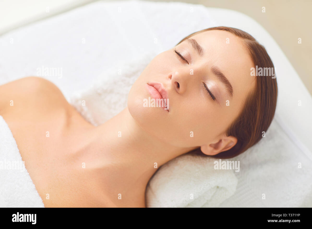 Beauty and spa concept. Brunette girl lying on a massage desk Stock Photo