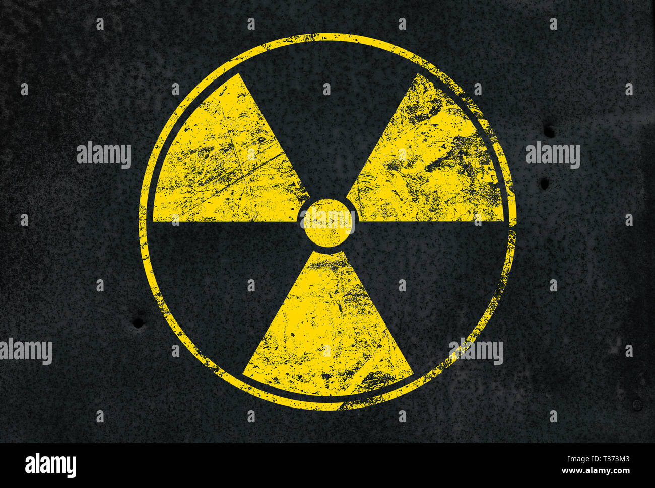 Yellow radioactive hazard warning sign painted over grunge black metal wall background with copy space Stock Photo
