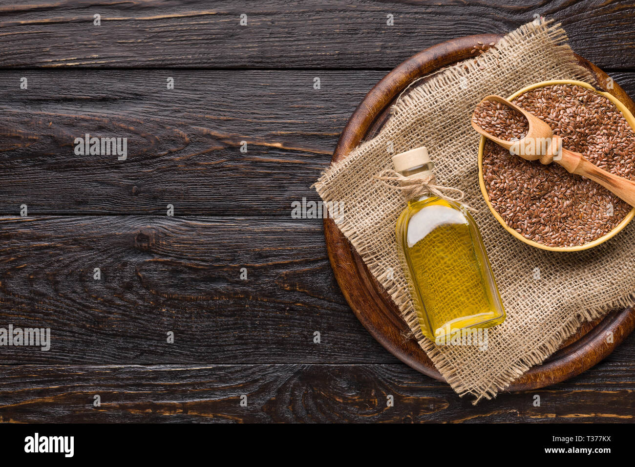 Linseed oil and bottle of linseeds on wooden background. Stock Photo