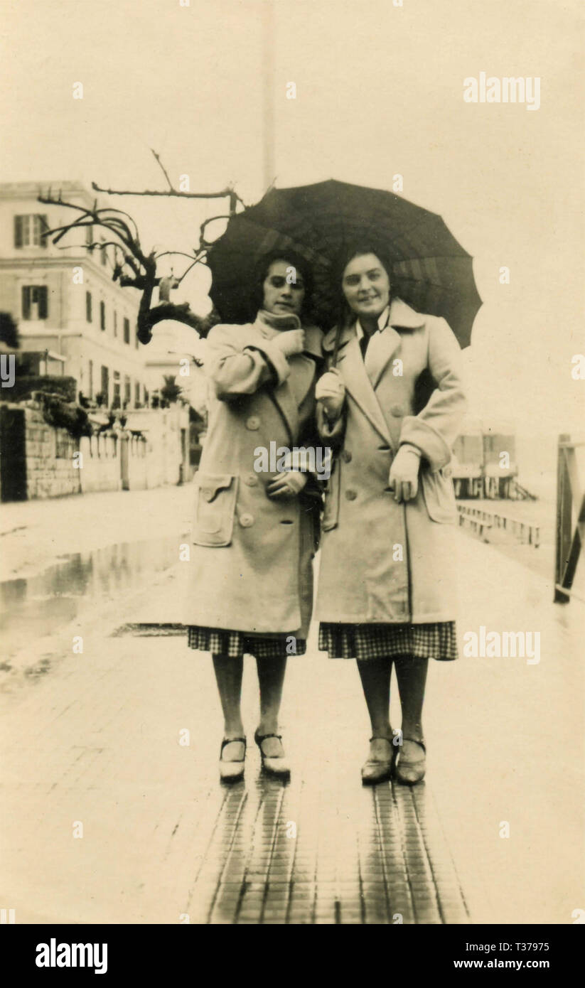 Women twins dressed alike under the same umbrella, Italy 1931 Stock