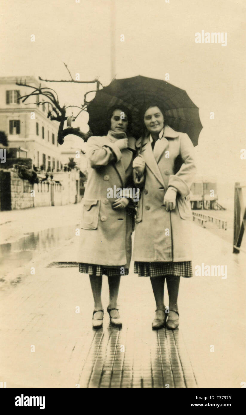 Women twins dressed alike under the same umbrella, Italy 1931 Stock Photo