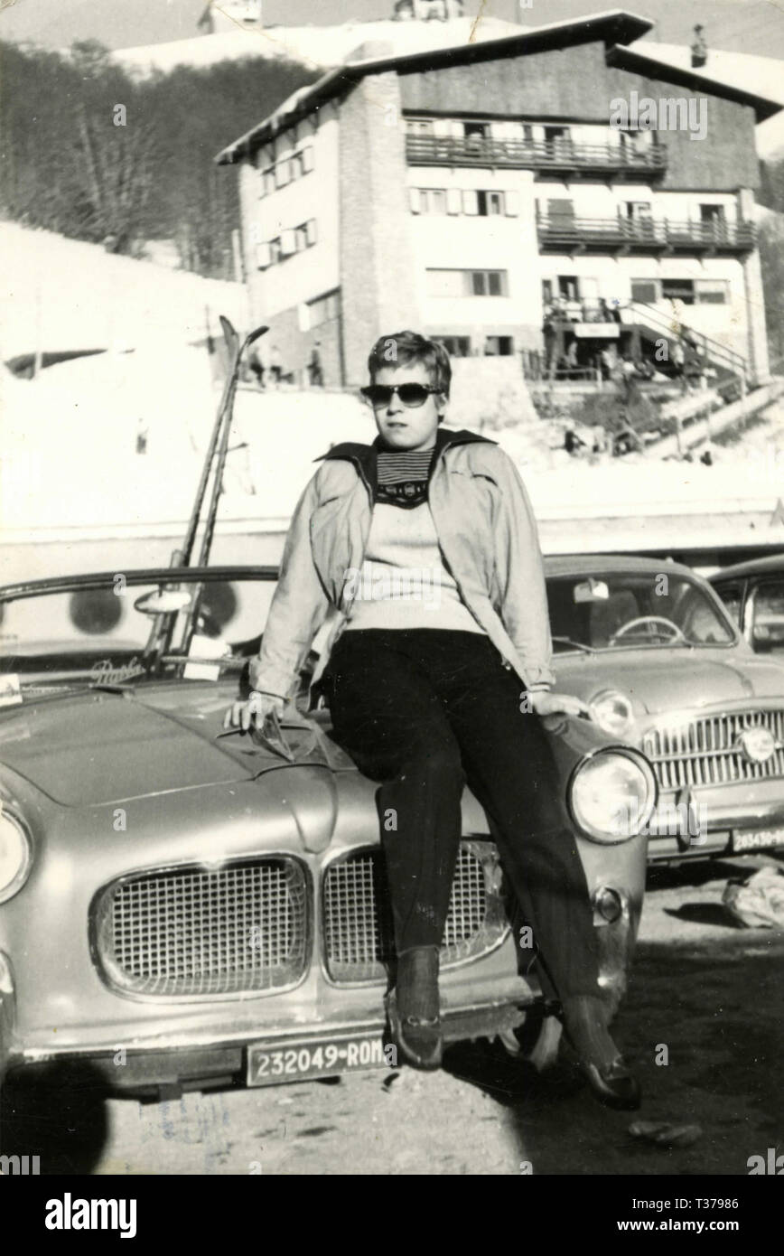 Woman sitting on a car at the skiing station, Italy 1950s Stock Photo