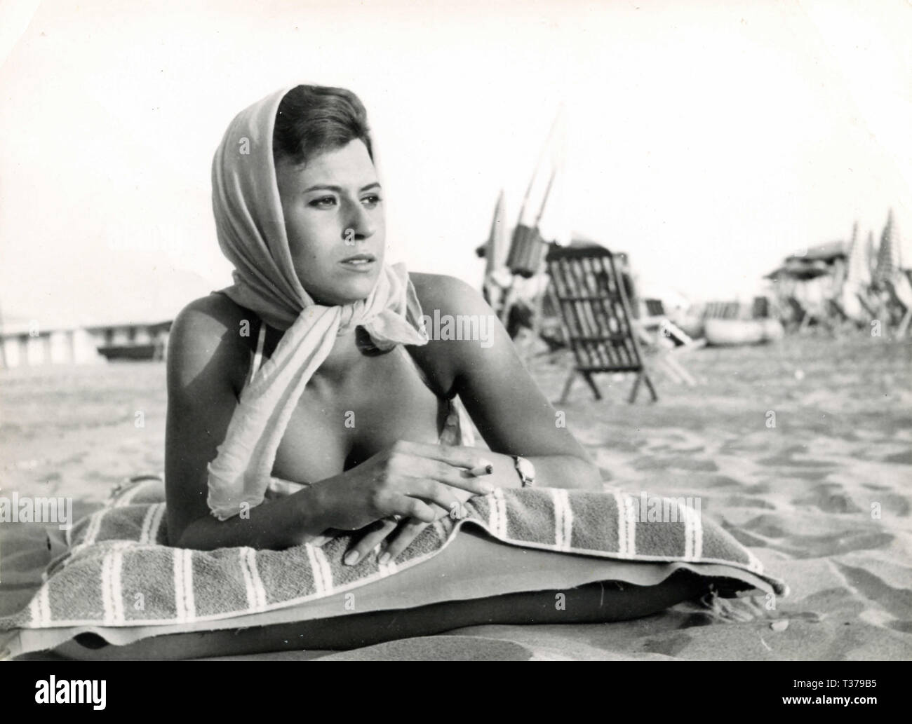 Woman with headscarf sunbathing at the beach, Italy 1960s Stock Photo