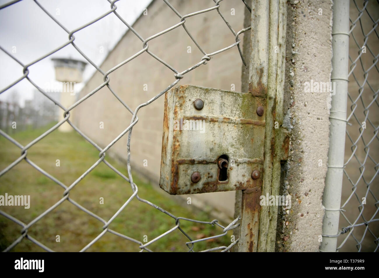 Locked gate in chain link fence, and watchtower in the perimeter of the