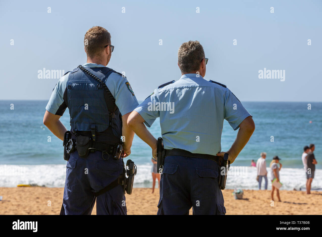 Two New South Wales police officers watch a surf rescue recovery on Palm beach,Sydney,Australia Stock Photo