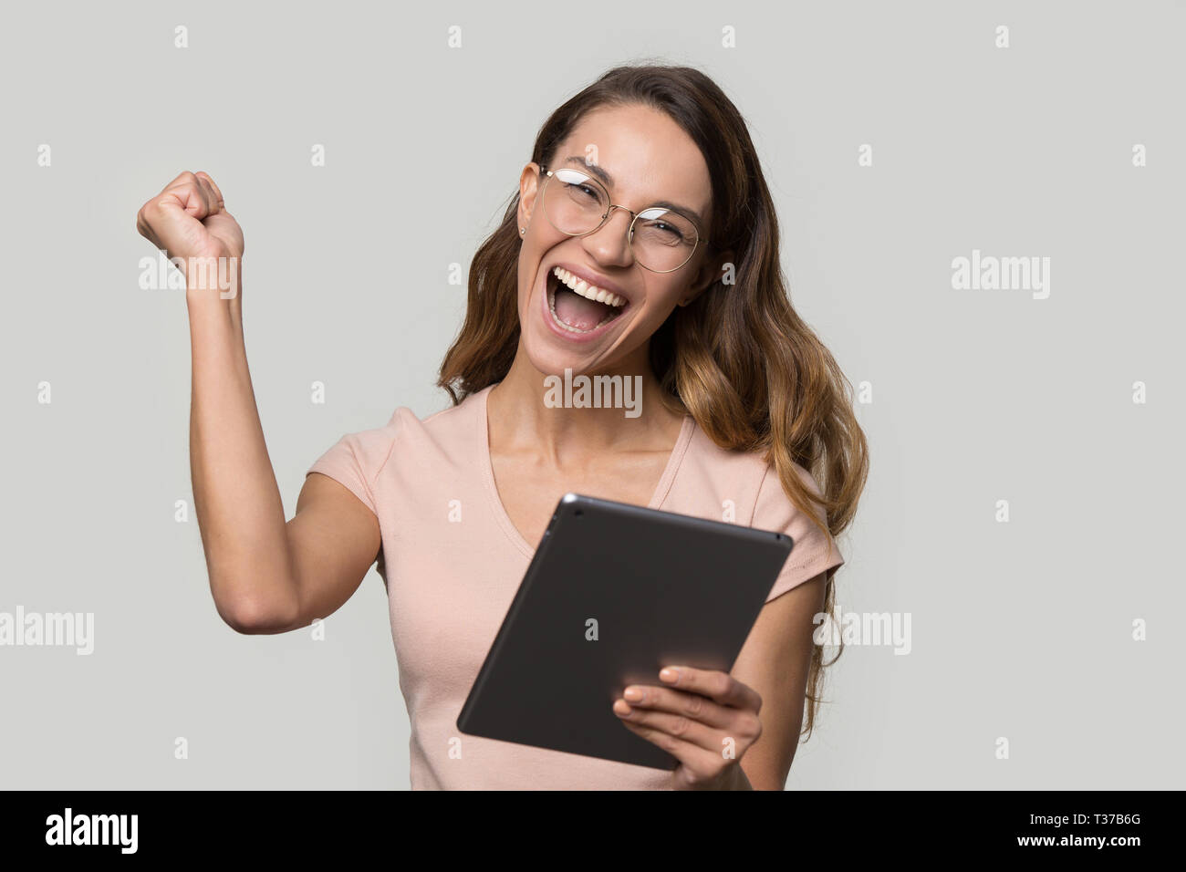 Happy woman in glasses holding digital tablet screaming celebrating win Stock Photo