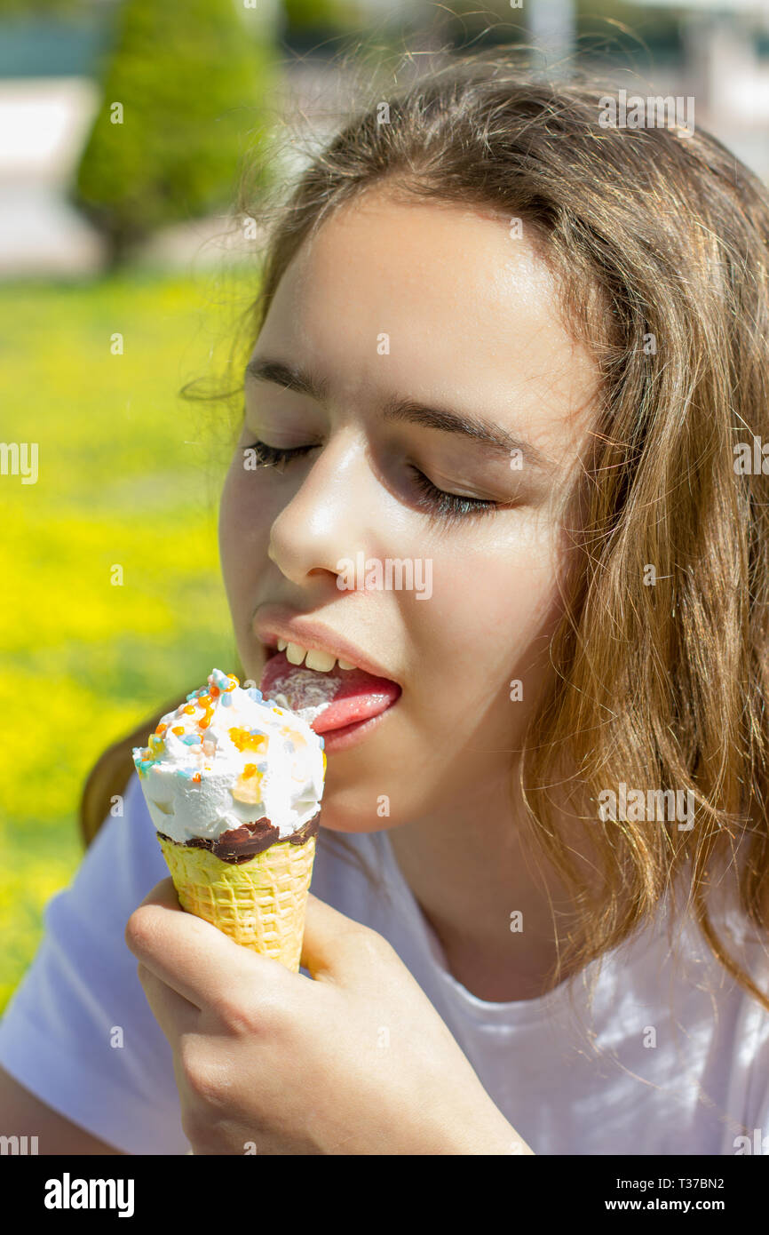 Beautiful teen girl eating ice cream in waffle cone in summer Stock Photo