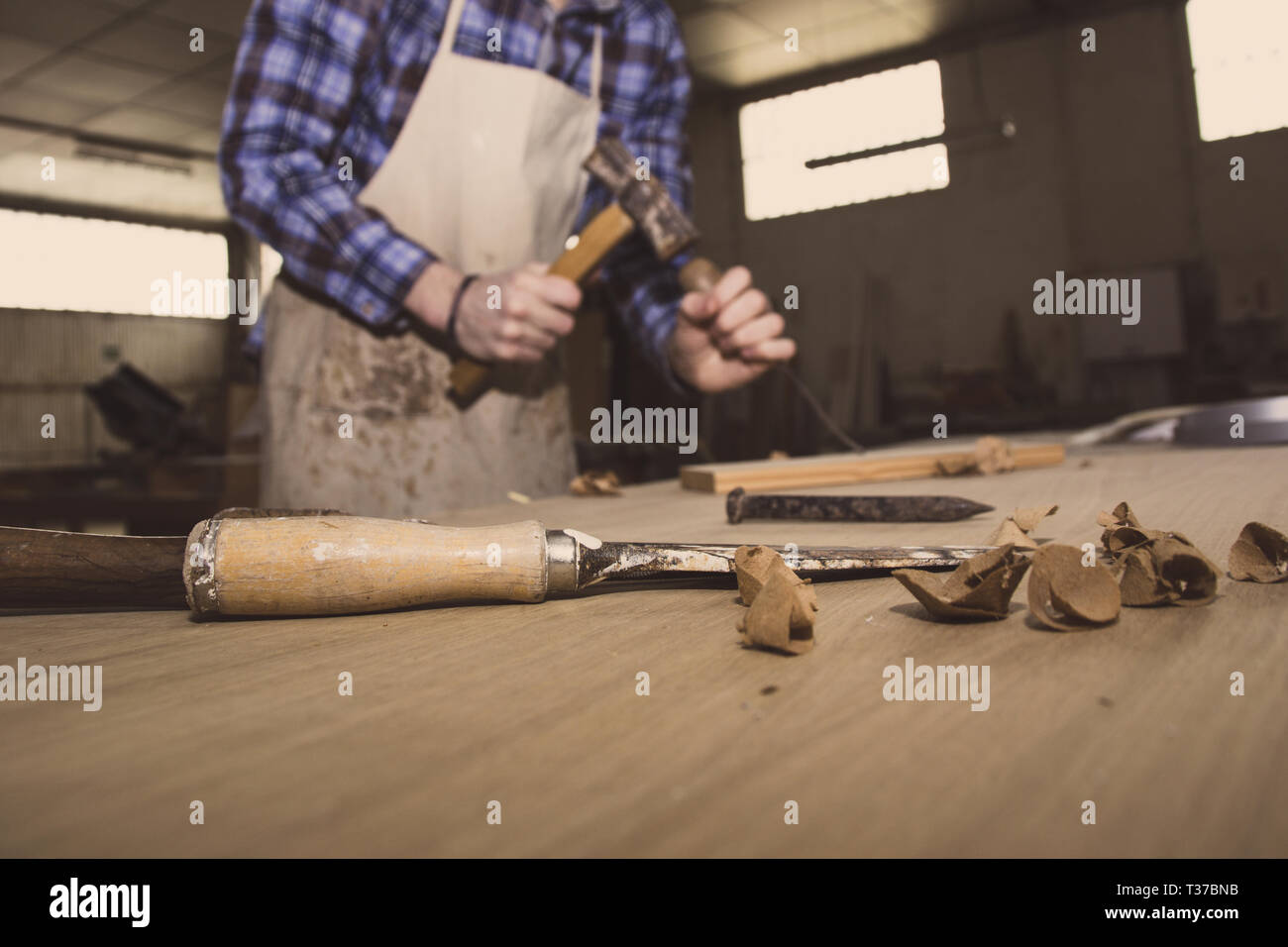 Carpenter working with hammer and chisel on wood table. Workshop  background. Carpenter workbench Stock Photo - Alamy