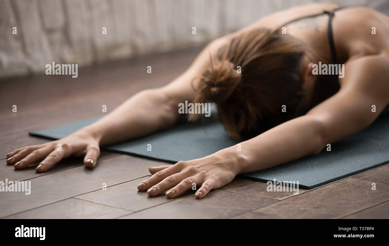 Attractive woman practicing yoga, relaxing after training, lying face