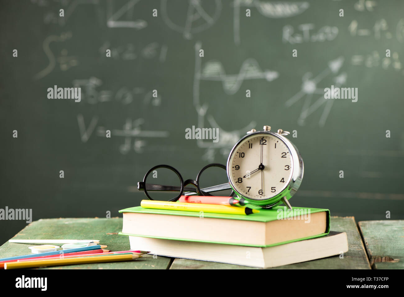 Back to school background with books and alarm clock over chalkboard ...