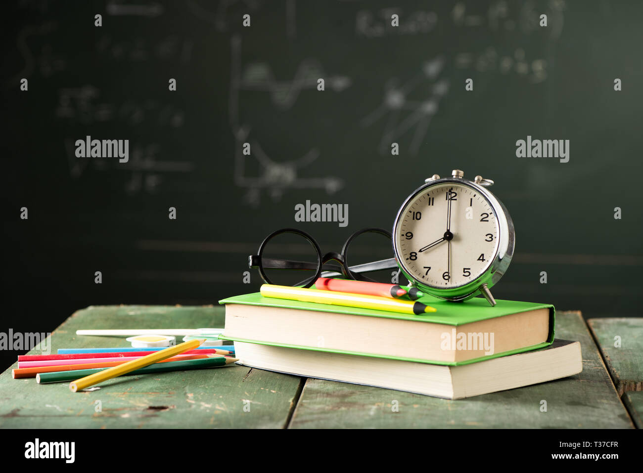 Back to school background with books and alarm clock over chalkboard ...