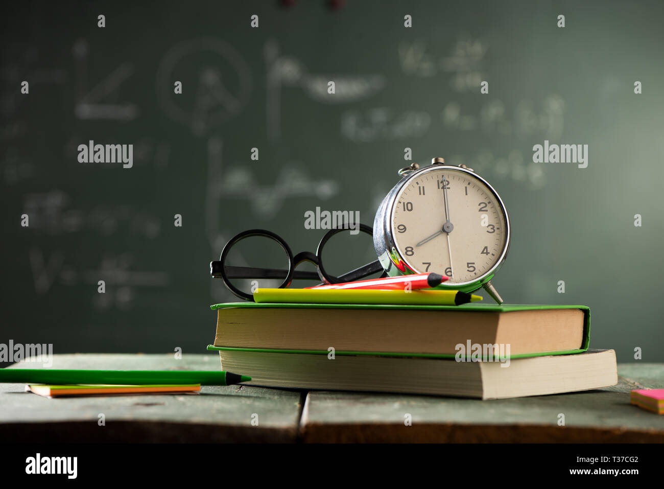 Back to school background with books and alarm clock over chalkboard ...