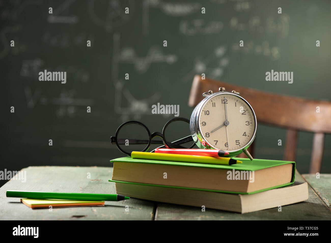 Back to school background with books and alarm clock over chalkboard ...