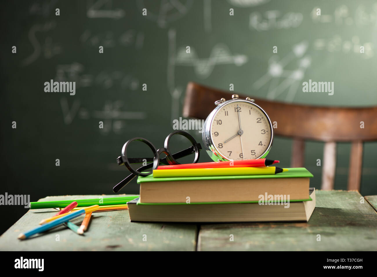 Back to school background with books and alarm clock over chalkboard ...