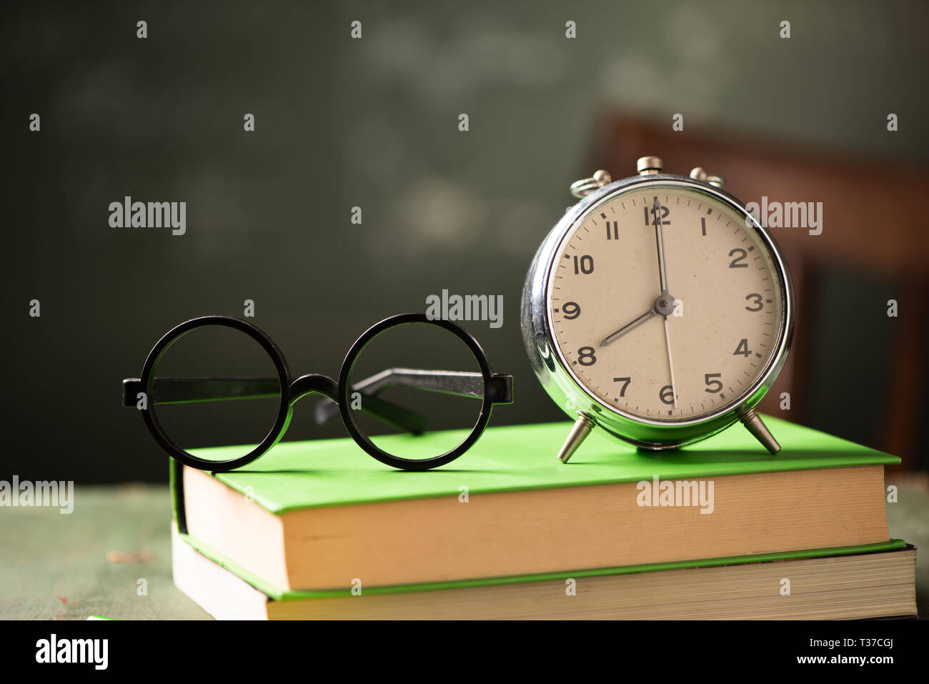 Back to school background with books and alarm clock over chalkboard ...