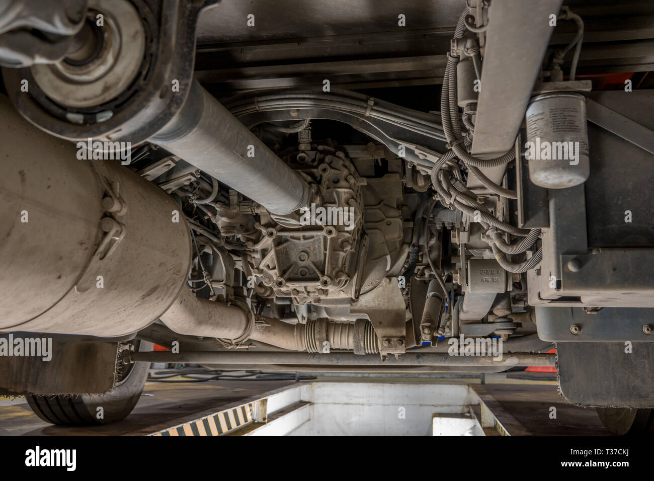 View of front axle and gearbox of a small truck from a maintenance pit
