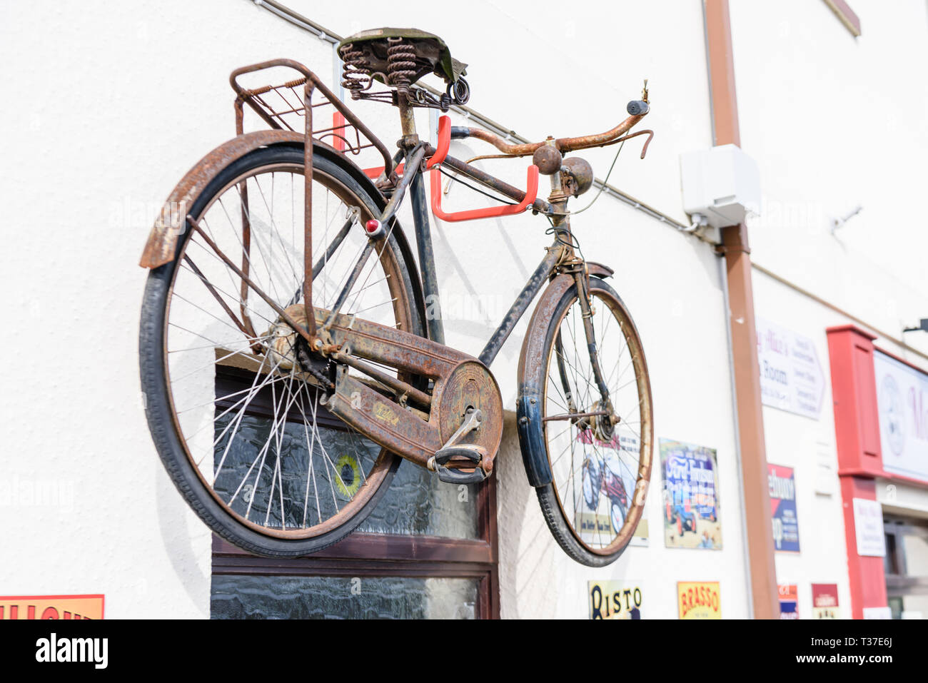 A bicycle and old fashioned metal advertising signs on the wall outside an Irish shop. Stock Photo