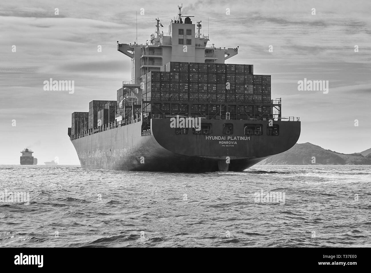 Black And White Photo Of The Giant Container Ship, Hyundai Platinum, Underway In The Busy East Lamma Channel, Hong Kong. Stock Photo