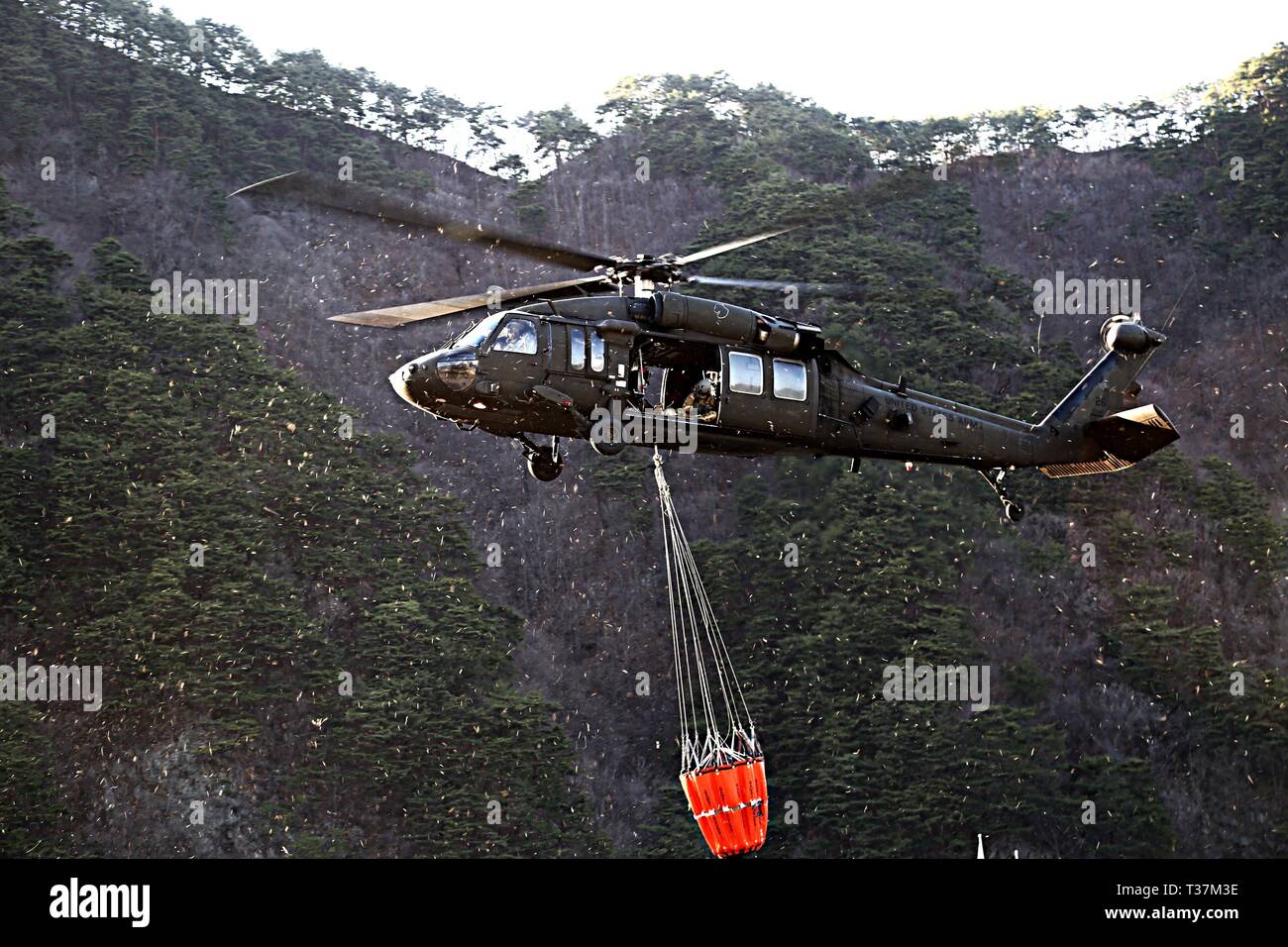 GANGWON, Republic of Korea – A UH-60 Black Hawk helicopter crew with 2-2 Assault Helicopter Battalion, 2nd Combat Aviation Brigade, 2nd Infantry Division/ROK-U.S. Combined Division, uses a Bambi bucket to drop water on the wildfire from the air in efforts to extinguish the blaze at Gangwon province, April 5. The effort is in partnership with Republic of Korea Army III Corps Command and other local agencies. (Courtesy photo by Republic of Korea Army Public Affairs) Stock Photo