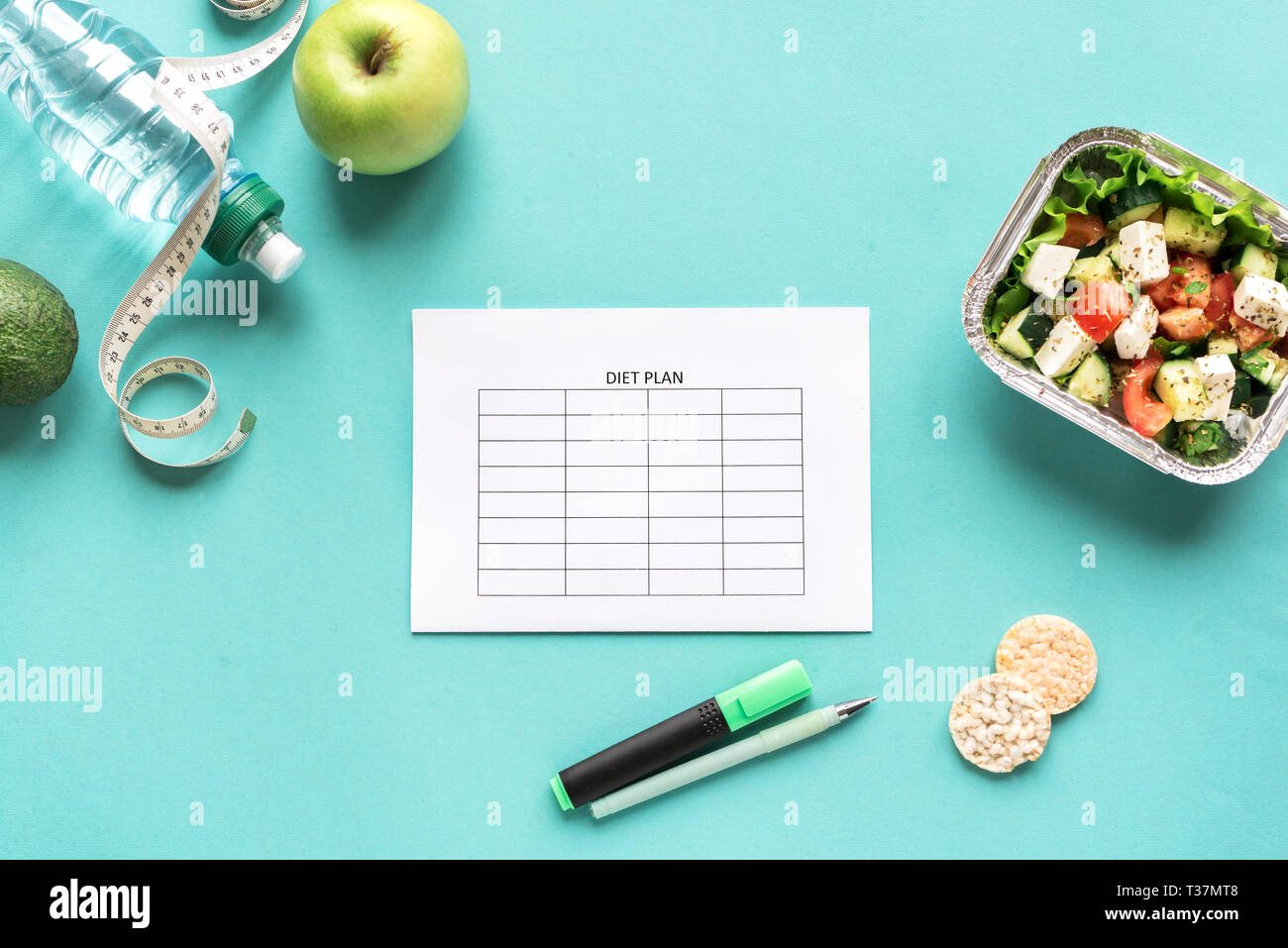 Diet meal plan mockup with water, fruits, salad and measuring tape. Fitness nutrition, diet concept on blue, top view, copy space. Stock Photo
