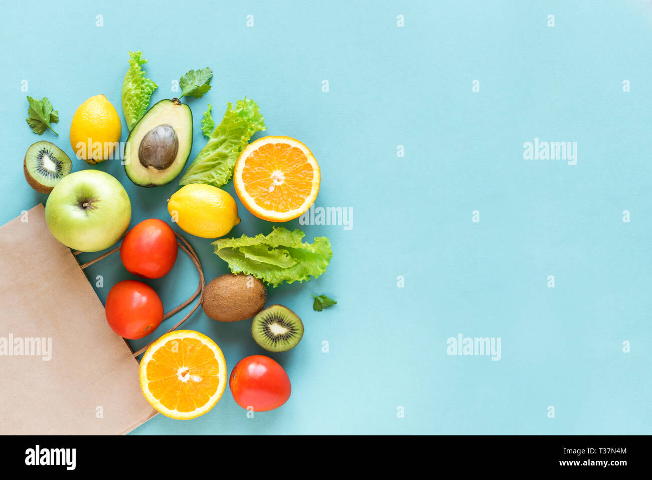 Healthy food background. Healthy food in paper bag vegetables and fruits on blue, copy space. Shopping food supermarket concept. Stock Photo
