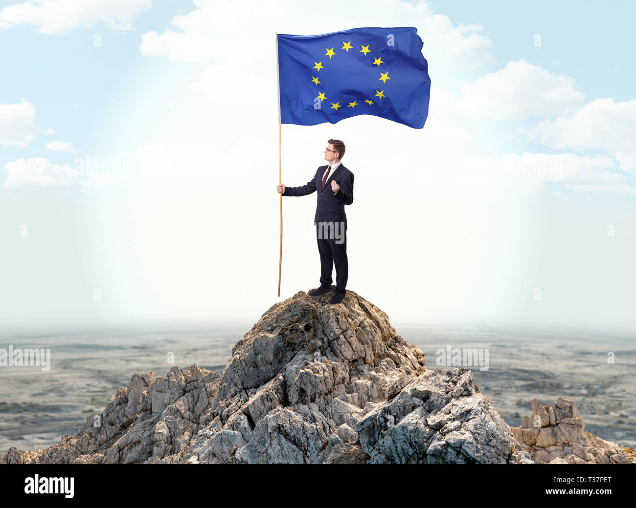Successful businessman on the top of a mountain holding victory flag ...