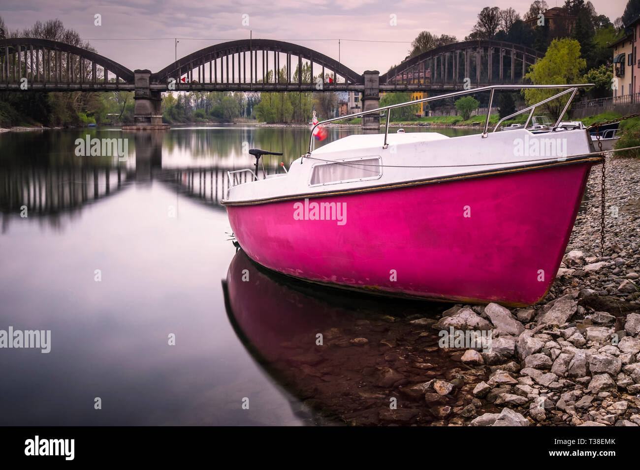 The pink boat moored alongside the Adda river, Brivio, Lecco, Italy Stock Photo