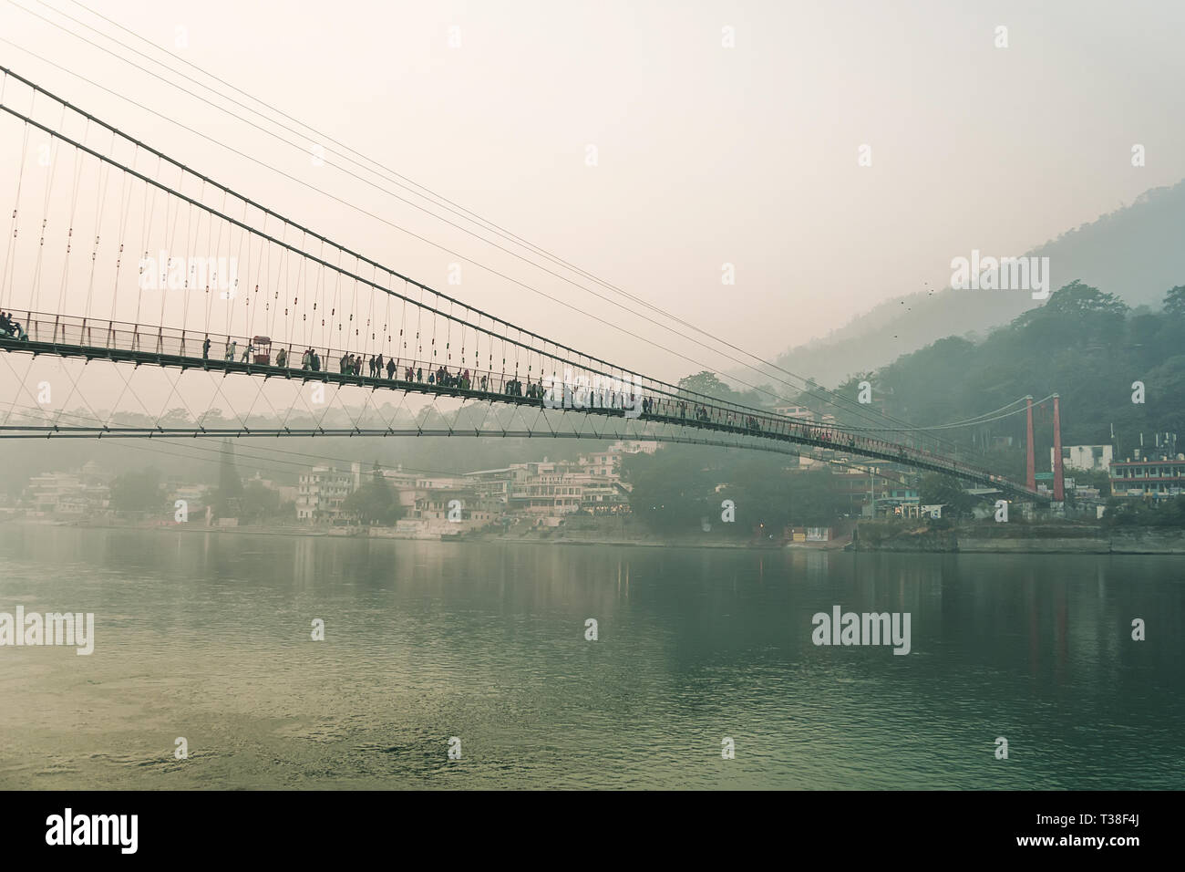 Ram Jhula is an iron suspension bridge situated in Rishikesh, Uttarakhand state of India. Evening dark landscape. Houses on the high slopes of the Him Stock Photo