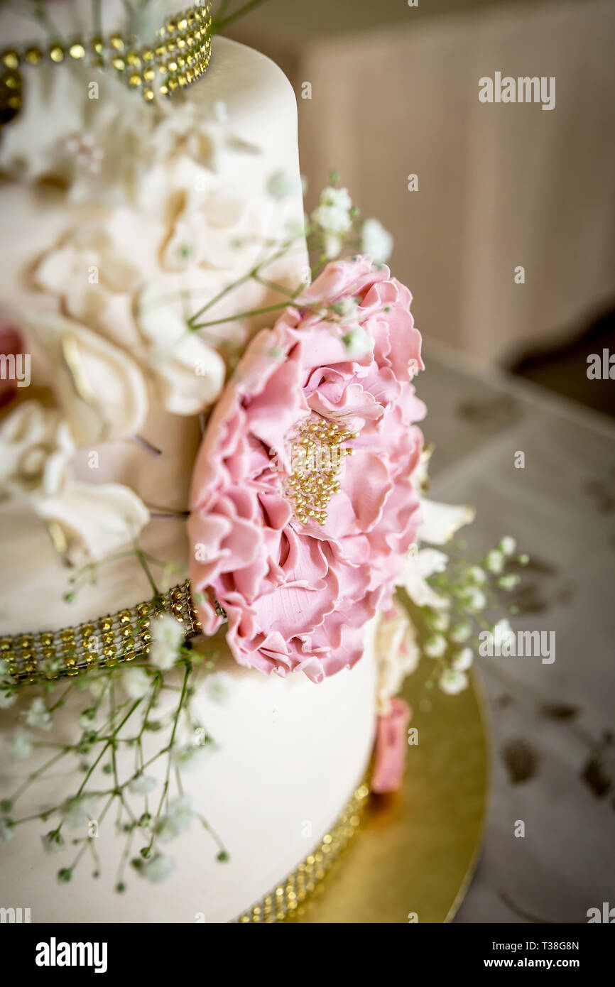 Wedding cake with white and pink sugar flowers and gold topper Stock Photo