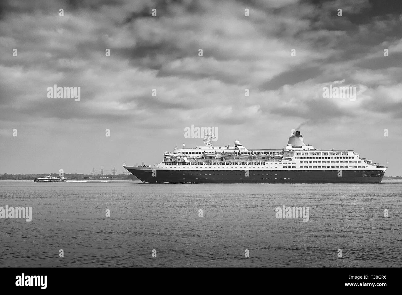 Black And White Photo Of The Saga Cruises (Saga Shipping), Cruise Ship, Saga Sapphire, Approaches The Port Of Southampton. A Fast Ferry Passes Ahead. Stock Photo