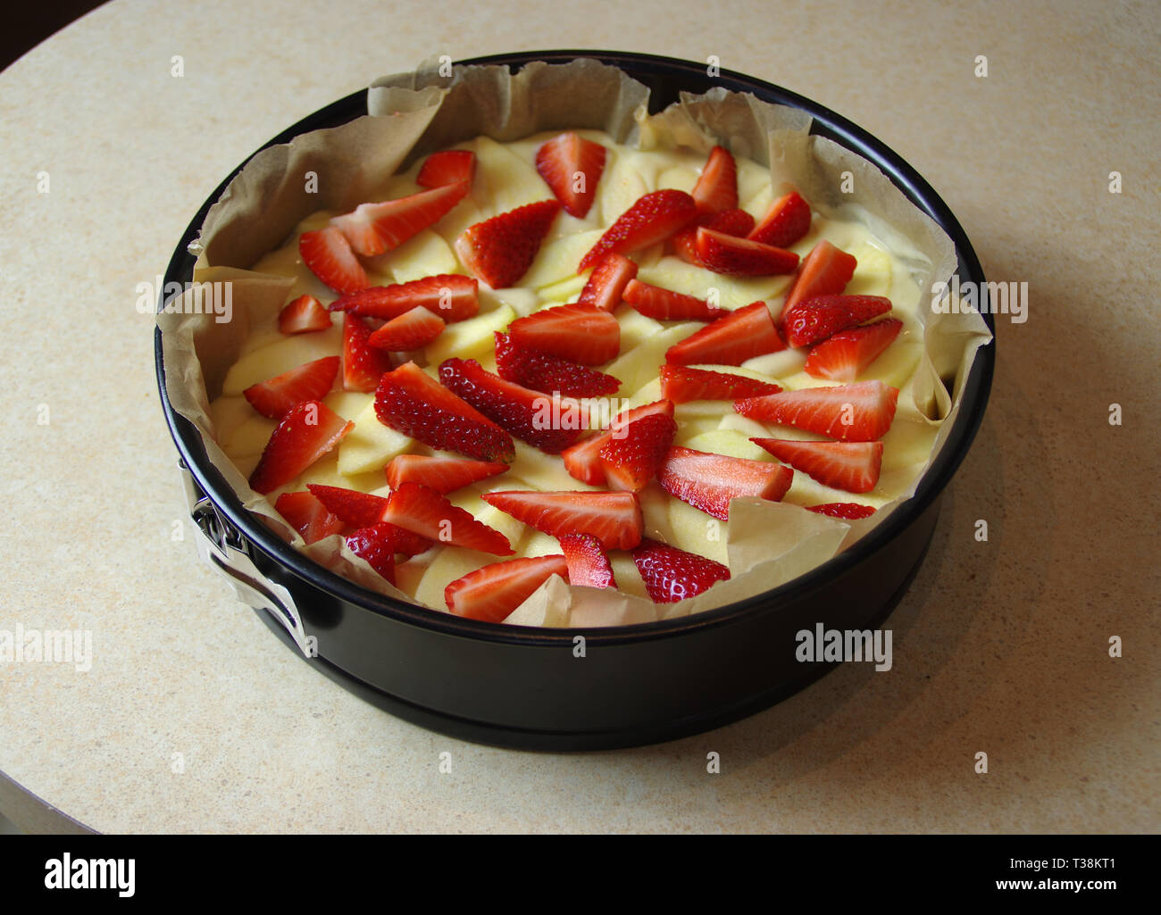 Preparing yeast cake with apple and strawberry to baking. Fresh raw homemade fruit pastry. Stock Photo