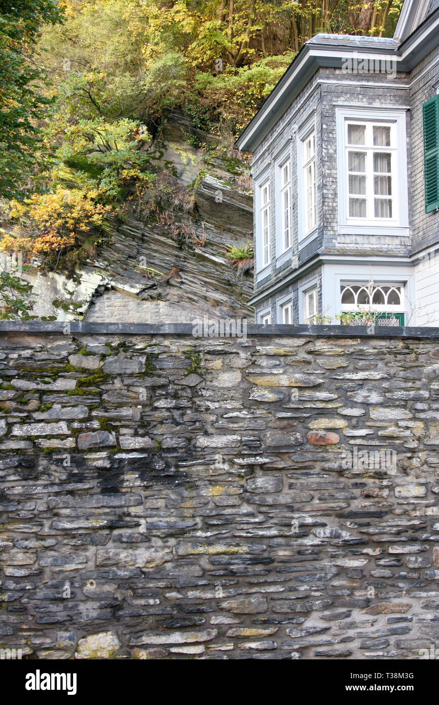 A high stone wall with house corner Stock Photo