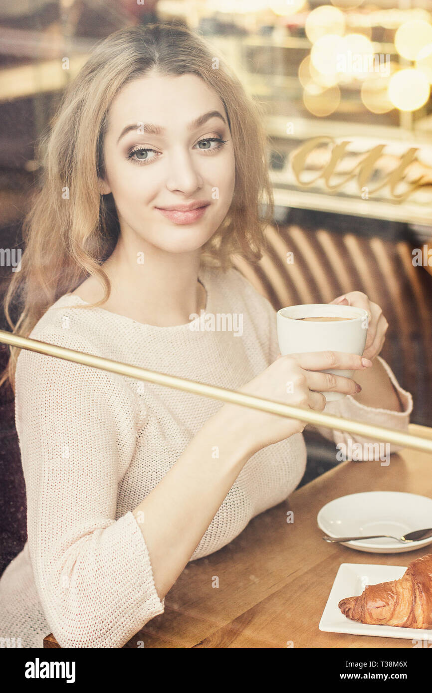 Portrait of beautiful girl drink coffee and looking through window