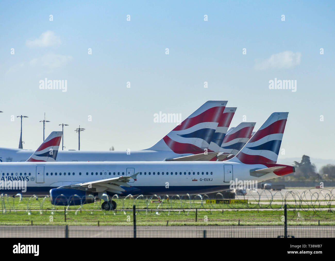 LONDON, ENGLAND - MARCH 2019: British Airways Airbus A321 airliner taxiing past tail fins of the airline's Boeing 747 Jumbo Jets  at London Heathrow A Stock Photo