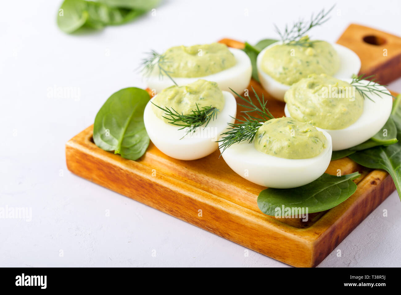 Deviled eggs with avocado and spinach on festive Easter table, close up, selective focus Stock Photo