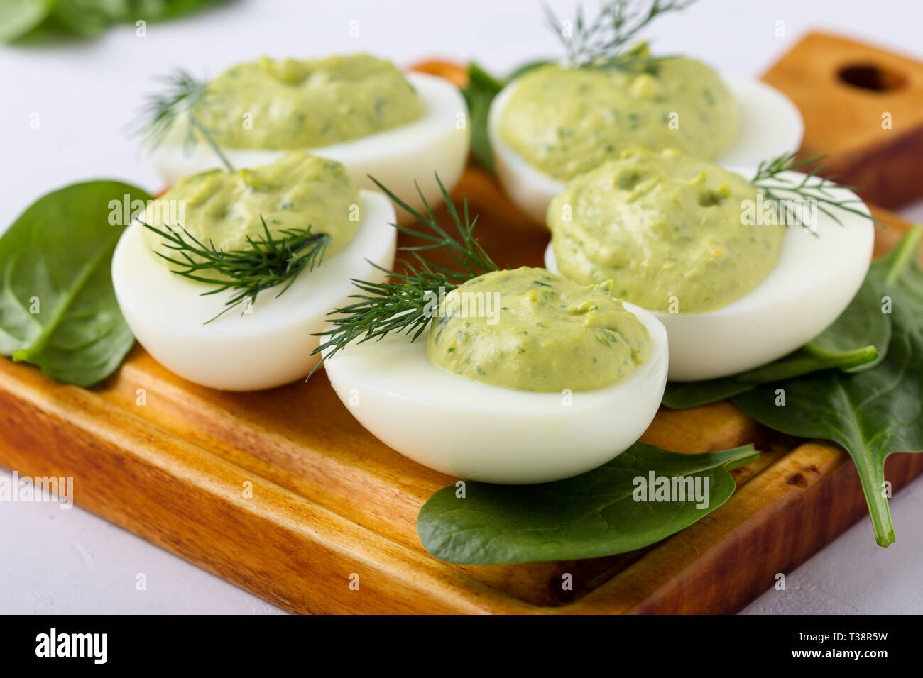 Deviled eggs with avocado and spinach on festive Easter table, close up, selective focus Stock Photo