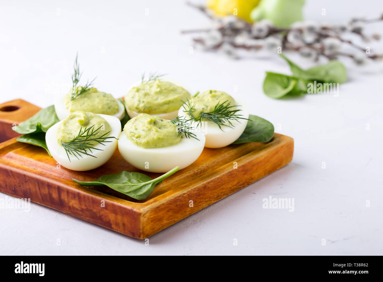 Deviled eggs with avocado and spinach on festive Easter table, close up, selective focus Stock Photo