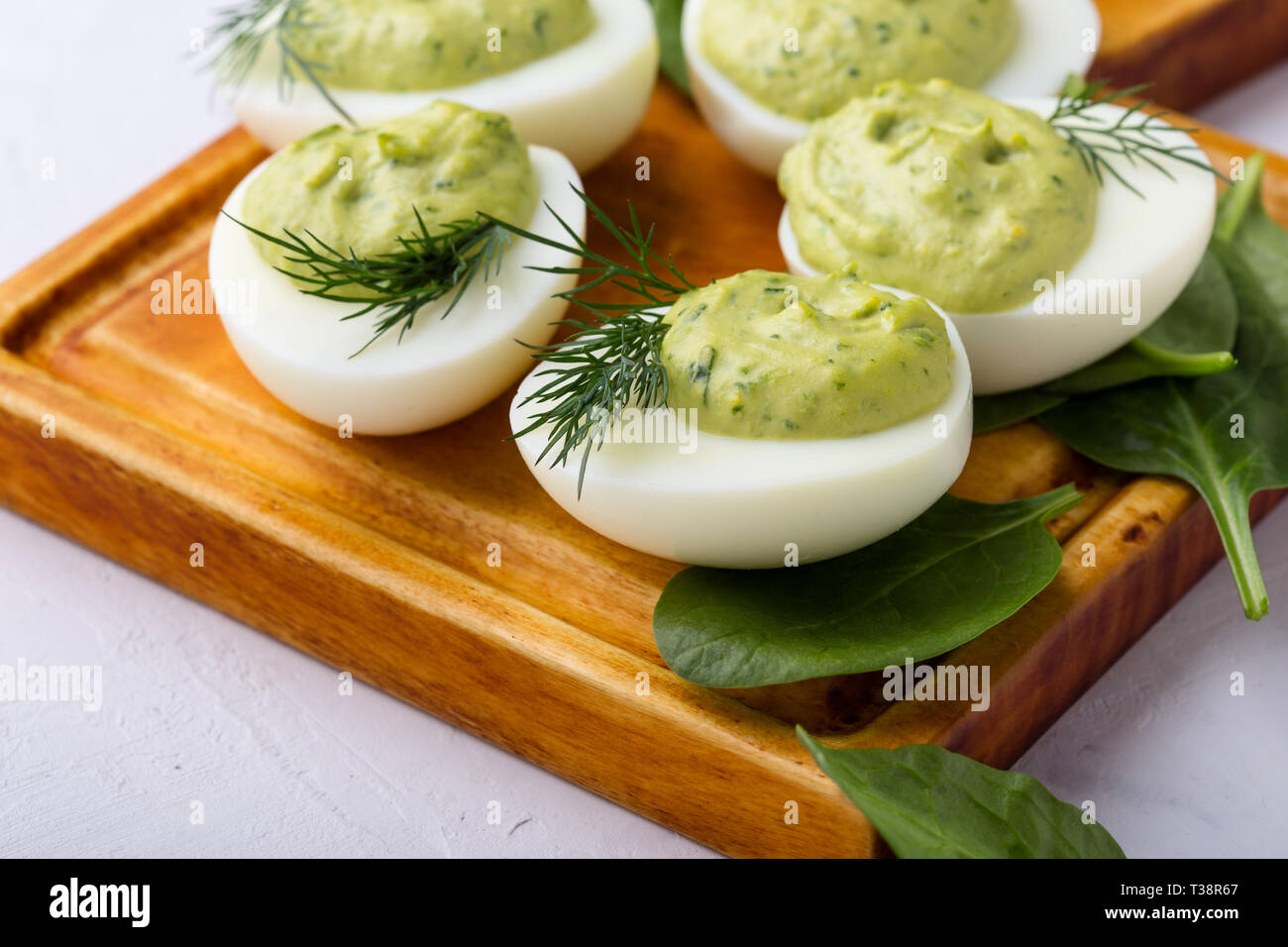 Deviled eggs with avocado and spinach on festive Easter table, close up, selective focus Stock Photo