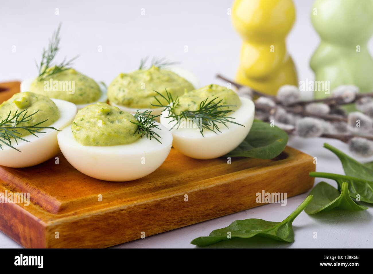 Deviled eggs with avocado and spinach on festive Easter table, close up, selective focus Stock Photo