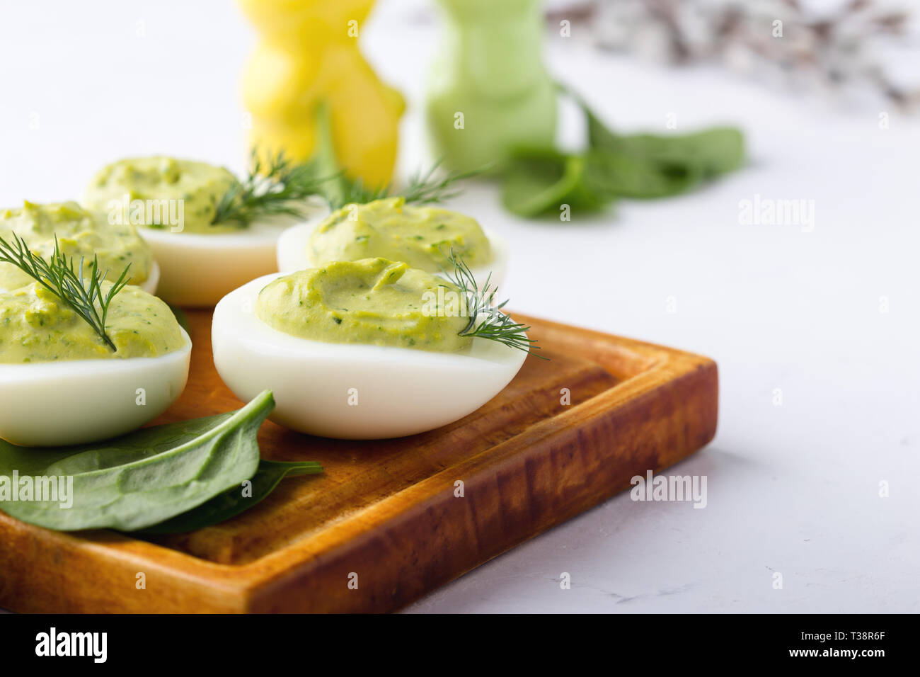 Deviled eggs with avocado and spinach on festive Easter table, close up, selective focus Stock Photo