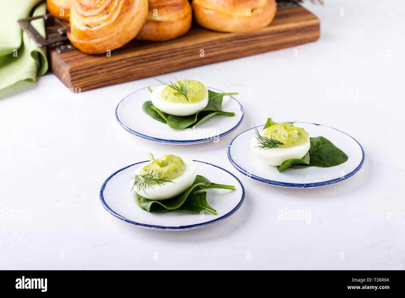 Deviled eggs with avocado and spinach and roll buns on festive Easter table, close up, selective focus Stock Photo