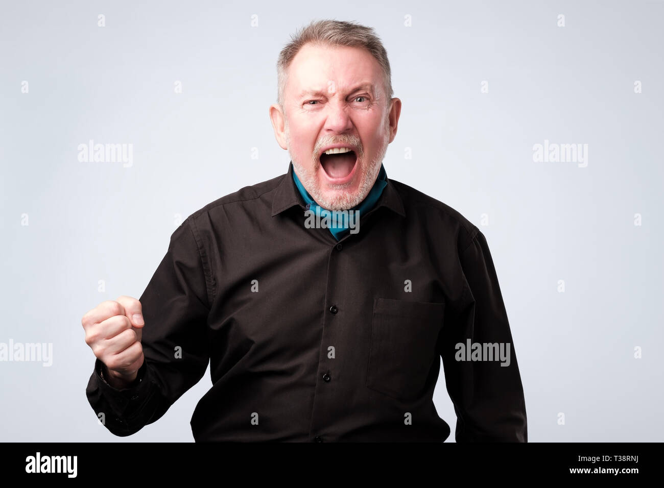Angry shocked man in black shirt screaming, isolated on white background. Stock Photo