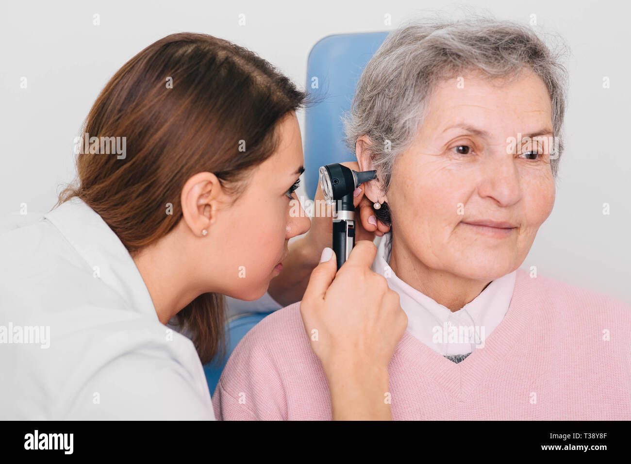 doctor examining elderly patient ear , using otoscope, in doctors office. Senior woman getting medical ear exam at clinic. Stock Photo
