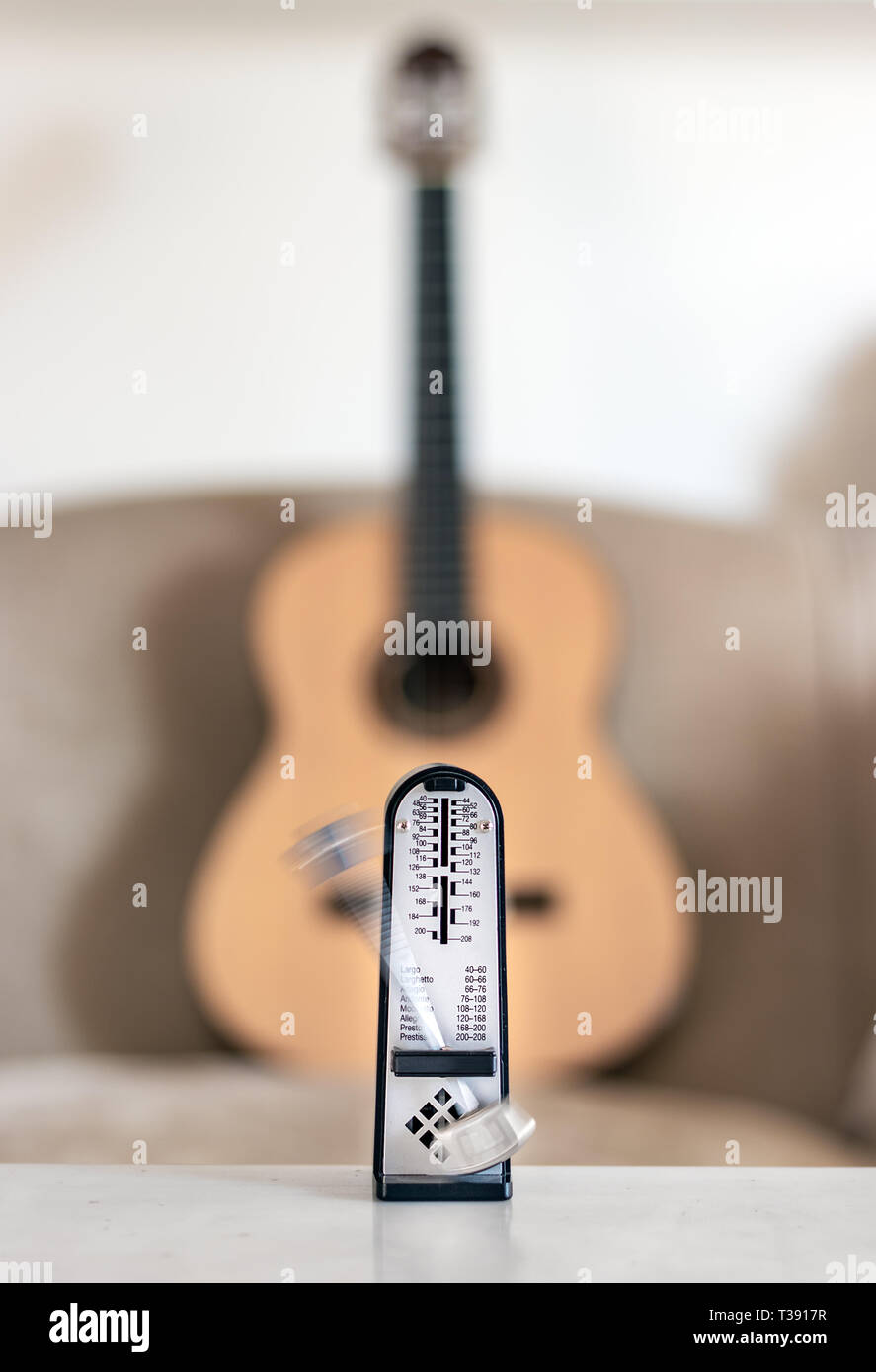 Mechanical metronome in motion, over a wooden classical acoustic guitar background Stock Photo