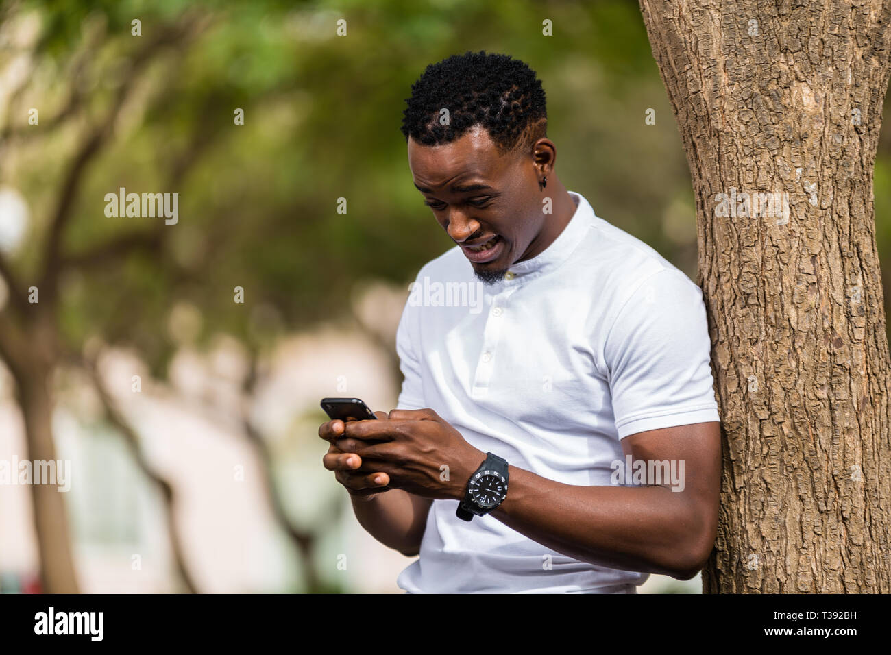 Outdoor portrait of a Young black African American men texting on ...