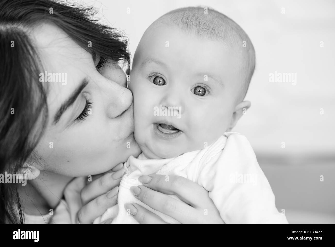 Young mother kiss her baby girl, close-up. Stock Photo