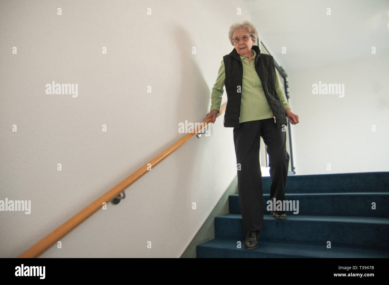 Senior woman walking down stairs Stock Photo